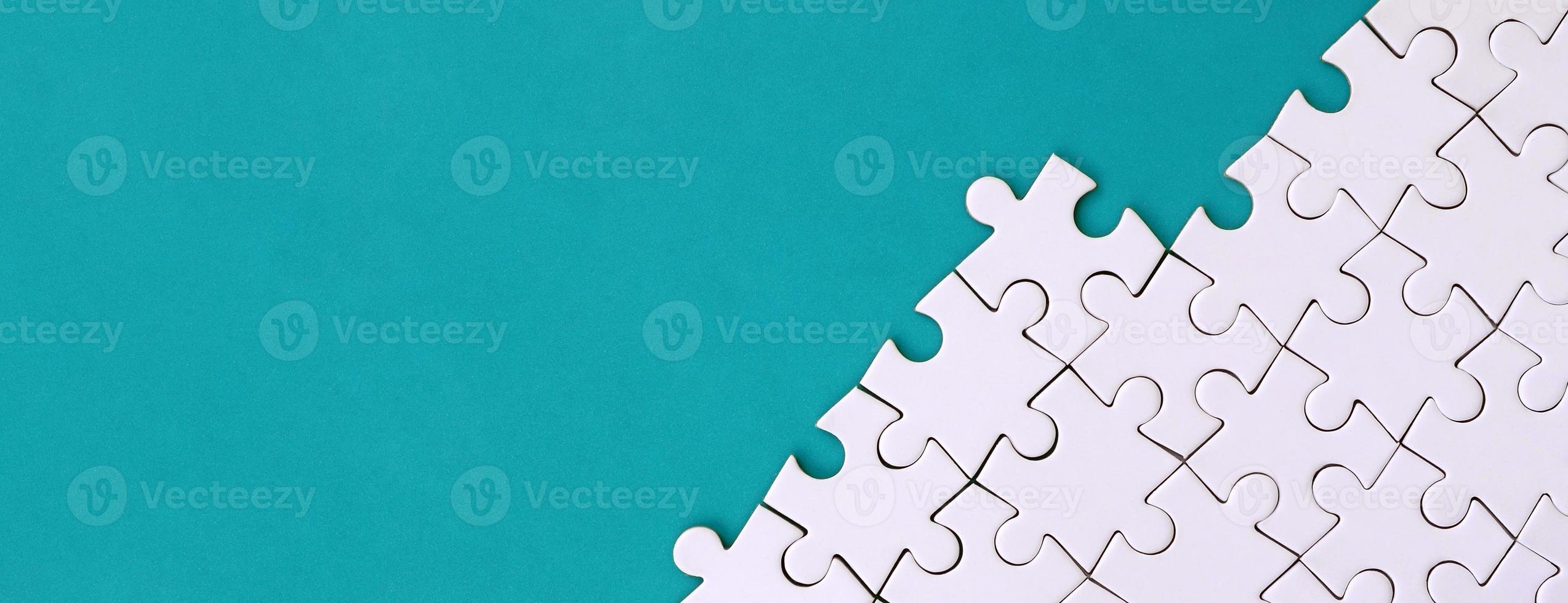 Fragment of a folded white jigsaw puzzle on the background of a blue plastic surface. Texture photo with copy space for text
