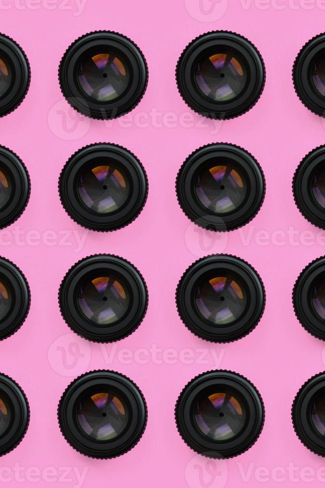 A few camera lenses with a closed aperture lie on texture background of fashion pastel pink color paper in minimal concept. Abstract trendy pattern photo