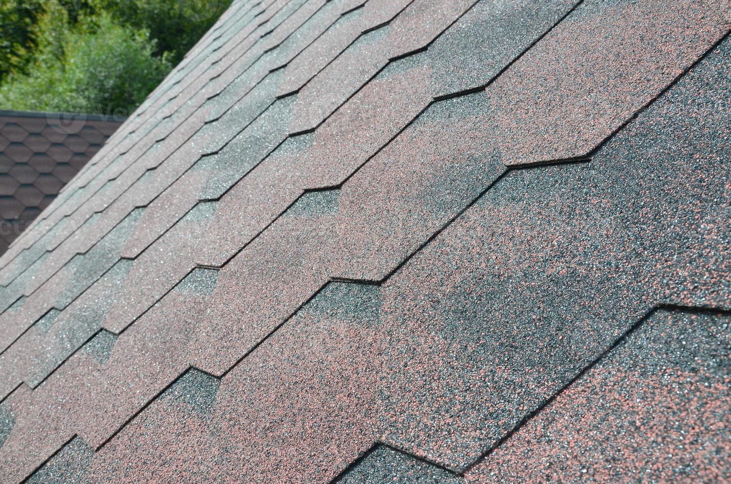 The texture of the roof with bituminous coating. Rough bituminous mosaic of red and brown flowers. Waterproof roofing photo