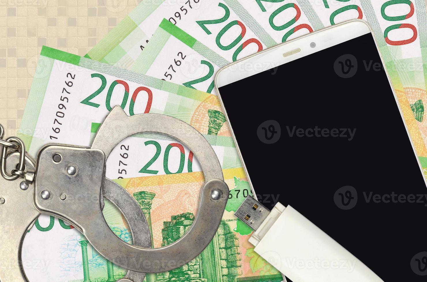 200 russian rubles bills and smartphone with police handcuffs. Concept of hackers phishing attacks, illegal scam or malware soft distribution photo