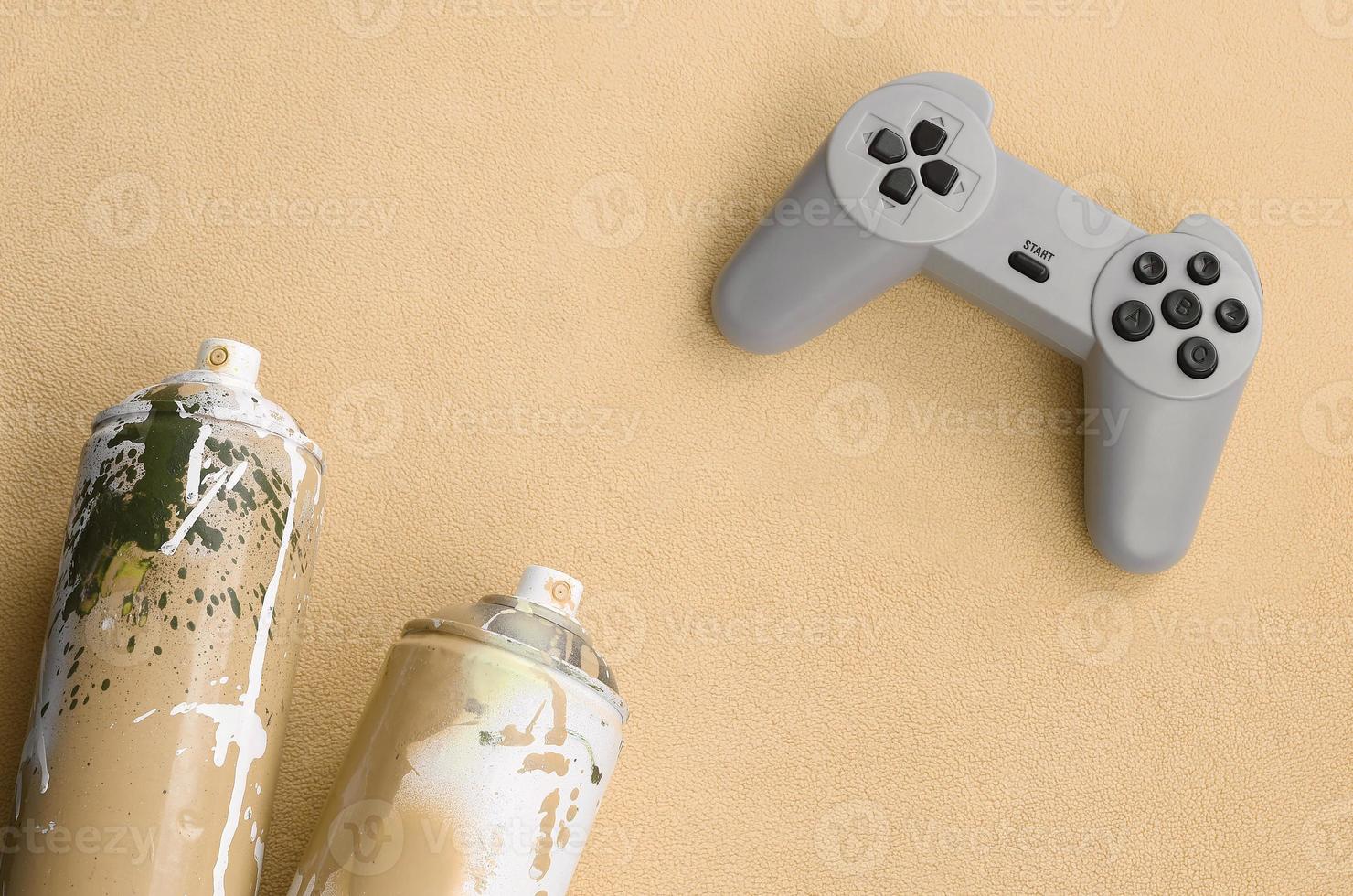 Teenagers and youth lifestyle concept. Joystick and two spray cans lies on the blanket of furry orange fleece fabric. Controllers for video games and paint cans on a plush fleece material background photo