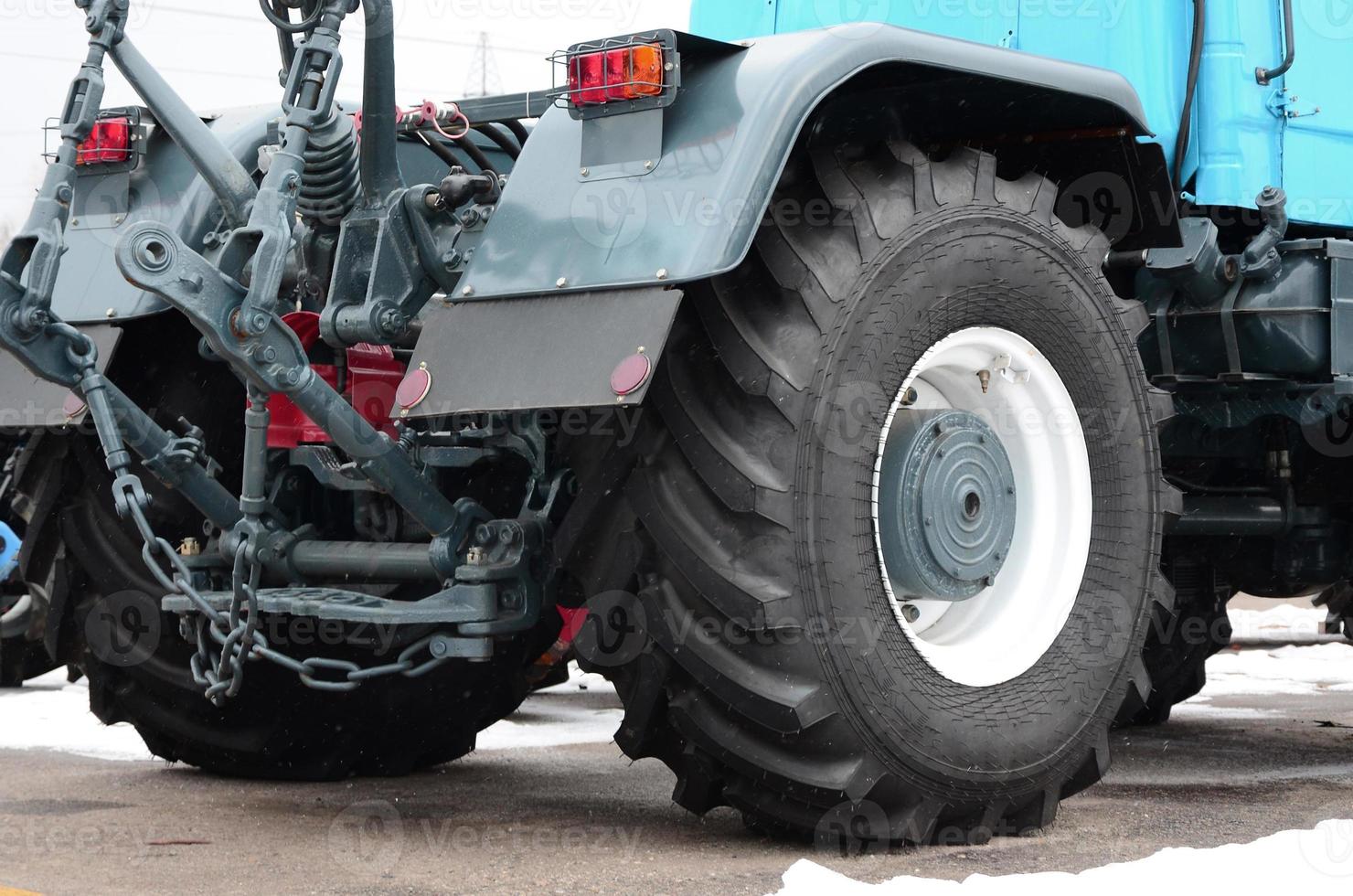 Wheels of back view of new tractor in snowy weather. Agricultural vehicle back photo