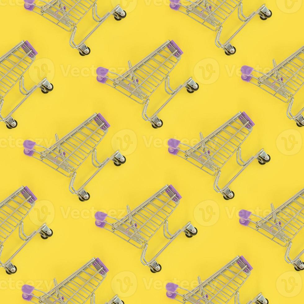 Shopping addiction, shopping lover or shopaholic concept. Many small empty shopping carts perform a pattern on a pastel colored paper background. Flat lay composition, top view photo