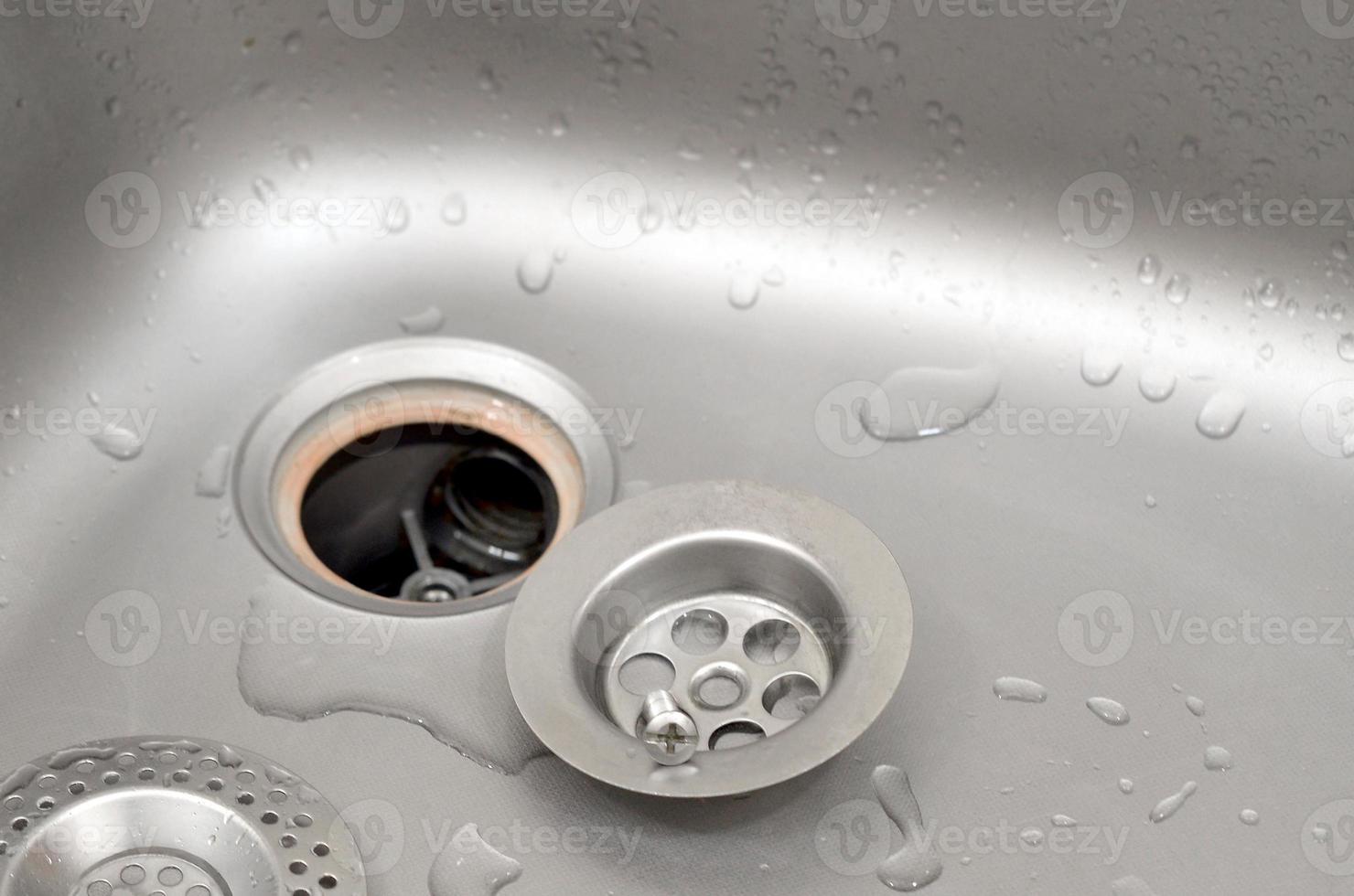 Silvery kitchen sink with a disassembled protective filter during the repair process photo