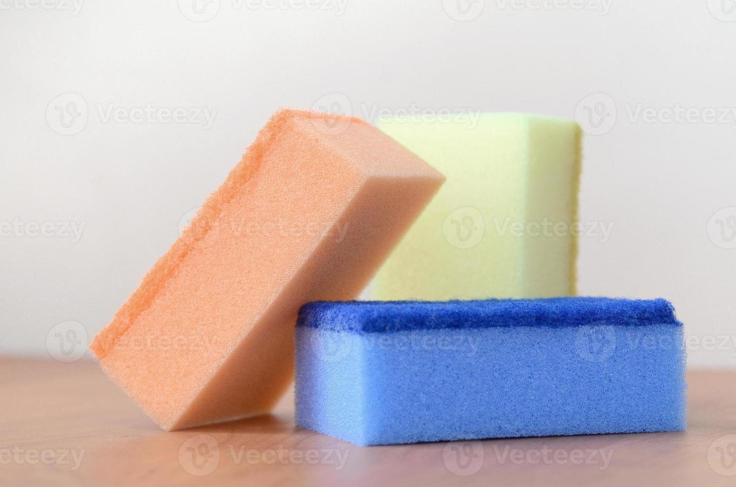 A few kitchen sponges lie on a wooden kitchen countertop. Colorful objects for washing dishes and cleaning in the house are ready for use photo