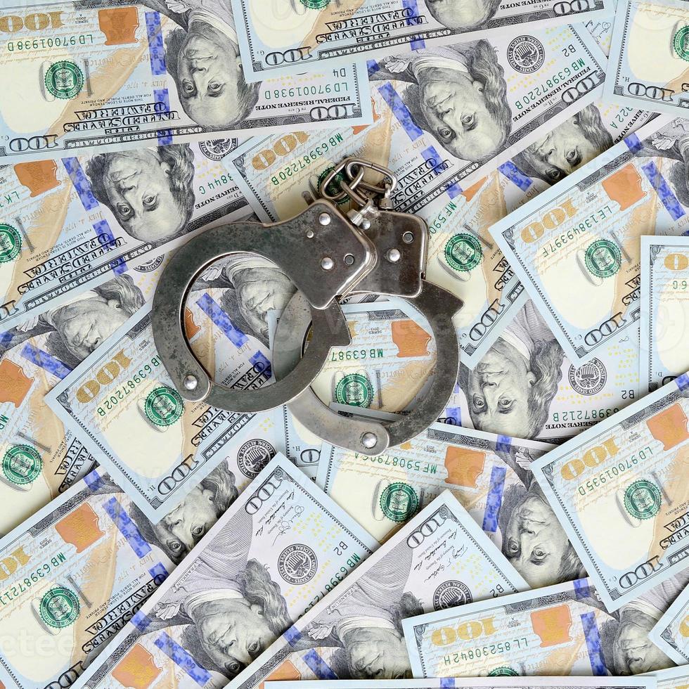 Silver police handcuffs lies on a many dollar bills photo