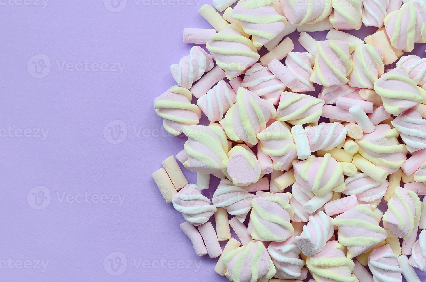 Colorful marshmallow laid out on violet paper background. pastel creative texture. minimal photo