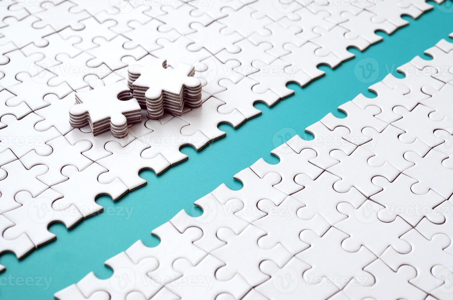 The blue path is laid on the platform of a white folded jigsaw puzzle. The missing elements of the puzzle are stacked nearby. Texture image with space for text photo