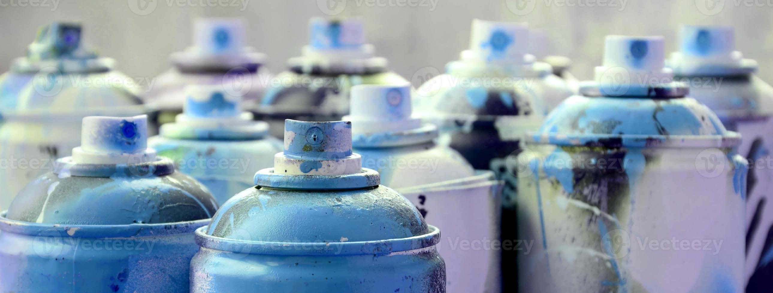 A lot of dirty and used aerosol cans of bright blue paint. Macro photograph with shallow depth of field. Selective focus on the spray nozzle photo