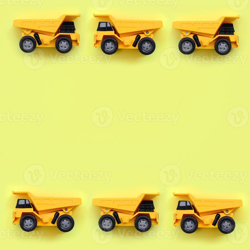 Many small yellow toy trucks on texture background of fashion pastel yellow color paper in minimal concept photo
