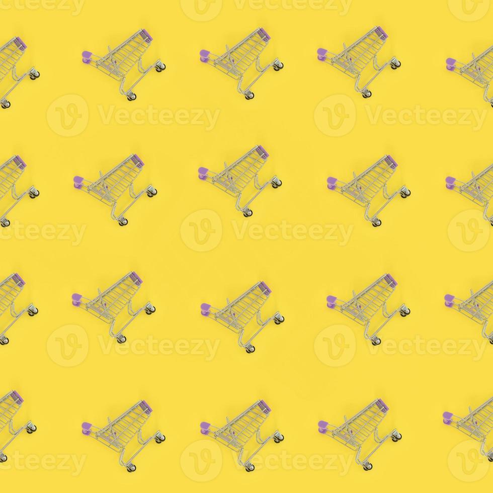 Shopping addiction, shopping lover or shopaholic concept. Many small empty shopping carts perform a pattern on a pastel colored paper background. Flat lay composition, top view photo