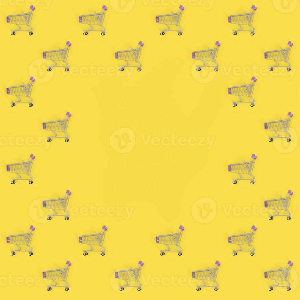 Shopping addiction, shopping lover or shopaholic concept. Many small empty shopping carts perform a pattern on a pastel colored paper background. Flat lay composition, top view photo