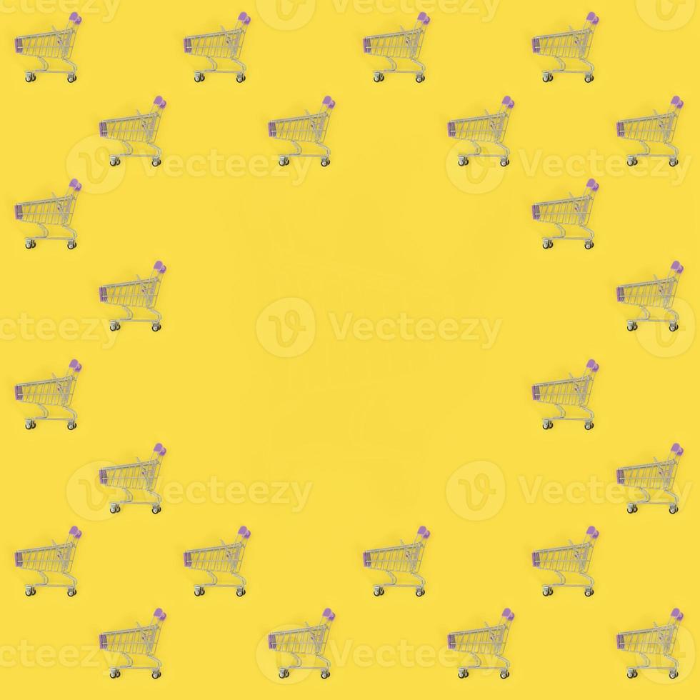 Shopping addiction, shopping lover or shopaholic concept. Many small empty shopping carts perform a pattern on a pastel colored paper background. Flat lay composition, top view photo