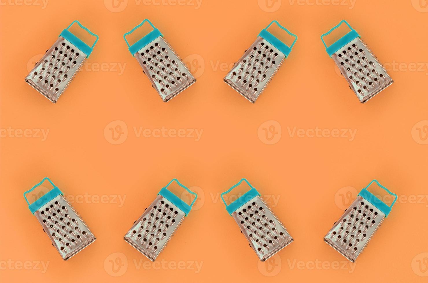 Small stainless steel graters lies on a pastel colored paper. Kitchen accessories. Tools for cooking. Flat lay top view photo