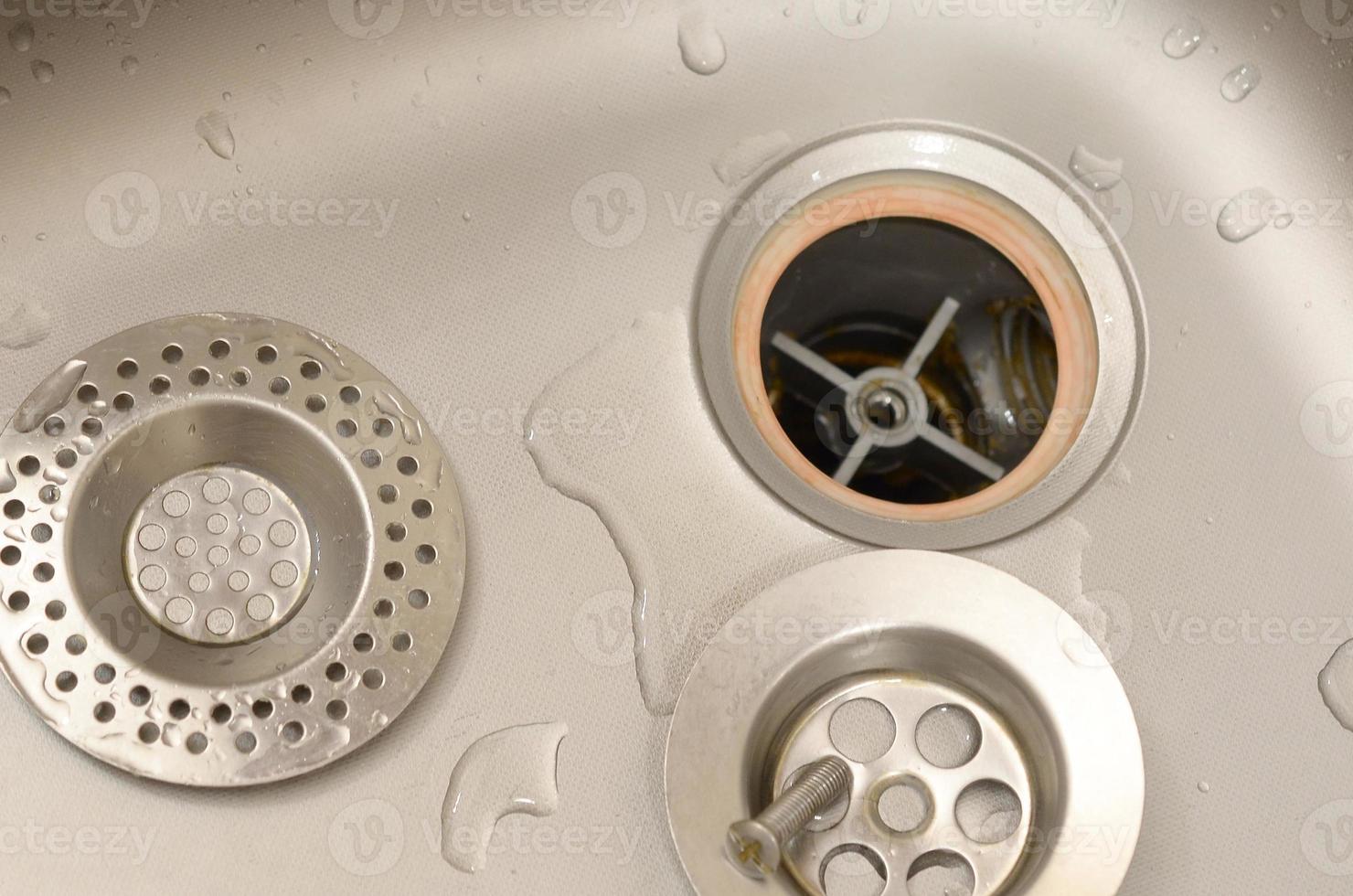 Silvery kitchen sink with a disassembled protective filter during the repair process photo