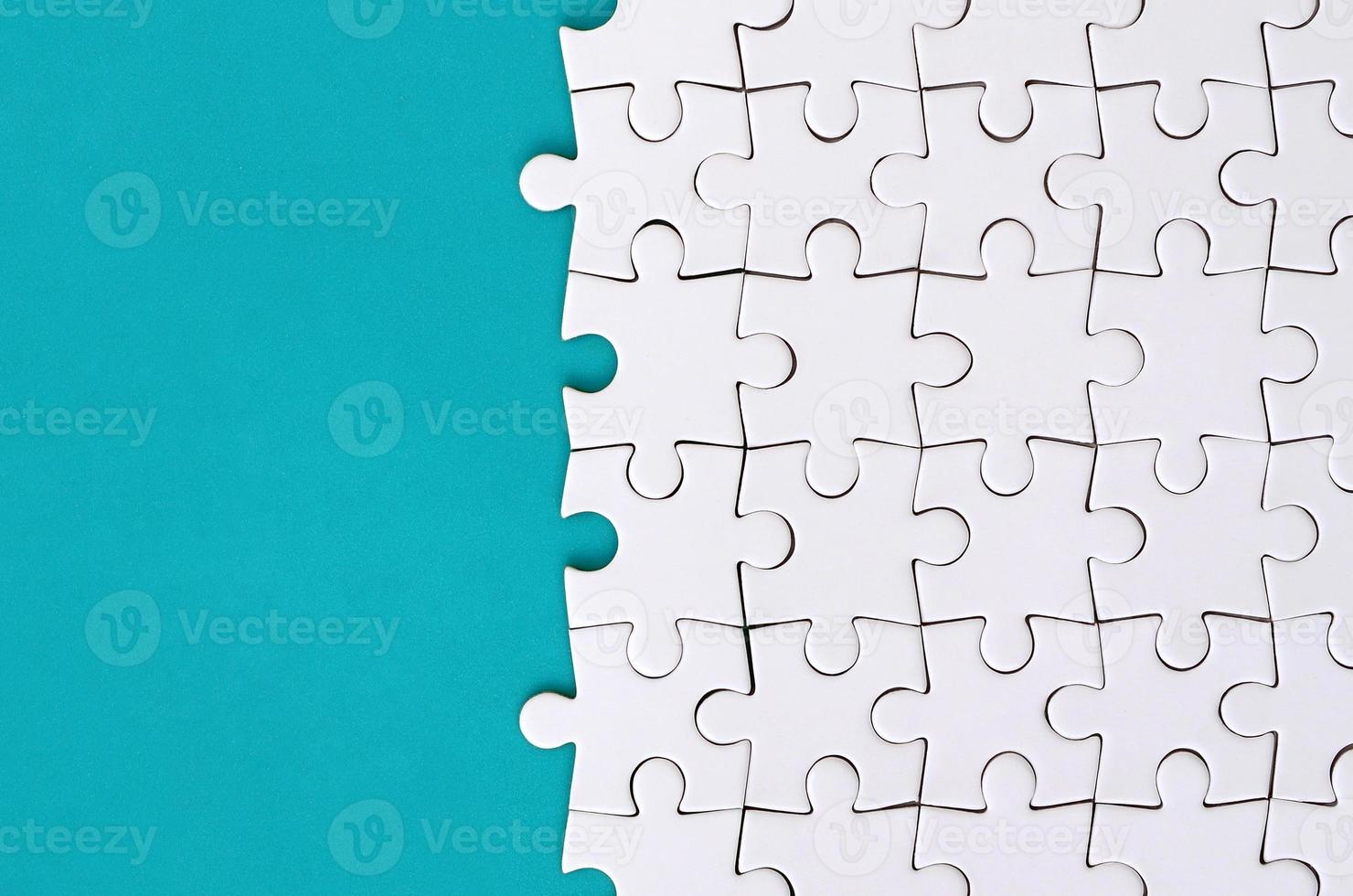 Fragment of a folded white jigsaw puzzle on the background of a blue plastic surface. Texture photo with copy space for text
