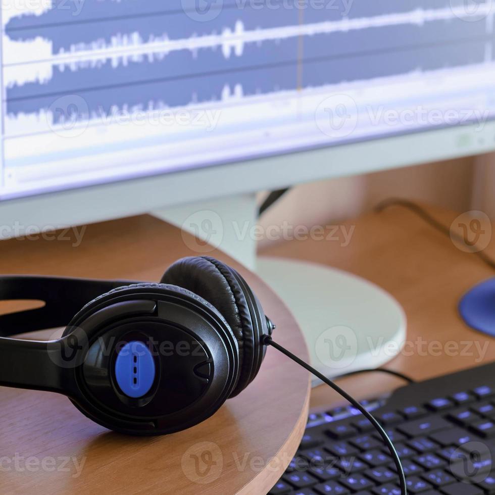 Big black headphones lie on the wooden desktop of the sound designer photo