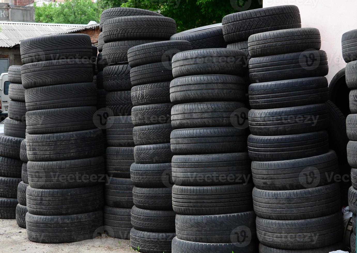 Old used tires stacked with high piles in secondary car parts shop garage photo