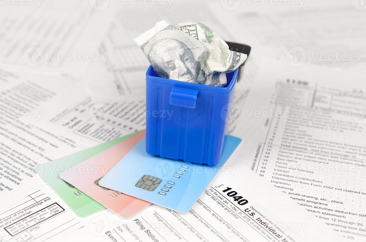 1040 Individual income tax return form and crumpled hundred dollar bill in trash bin on credit cards photo