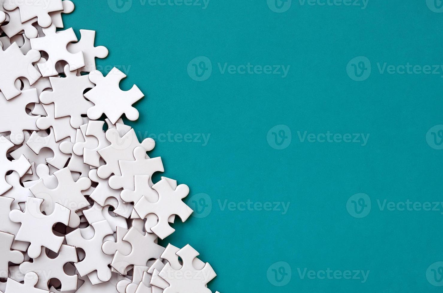 A pile of uncombed elements of a white jigsaw puzzle lies on the background of a blue surface. Texture photo with copy space for text