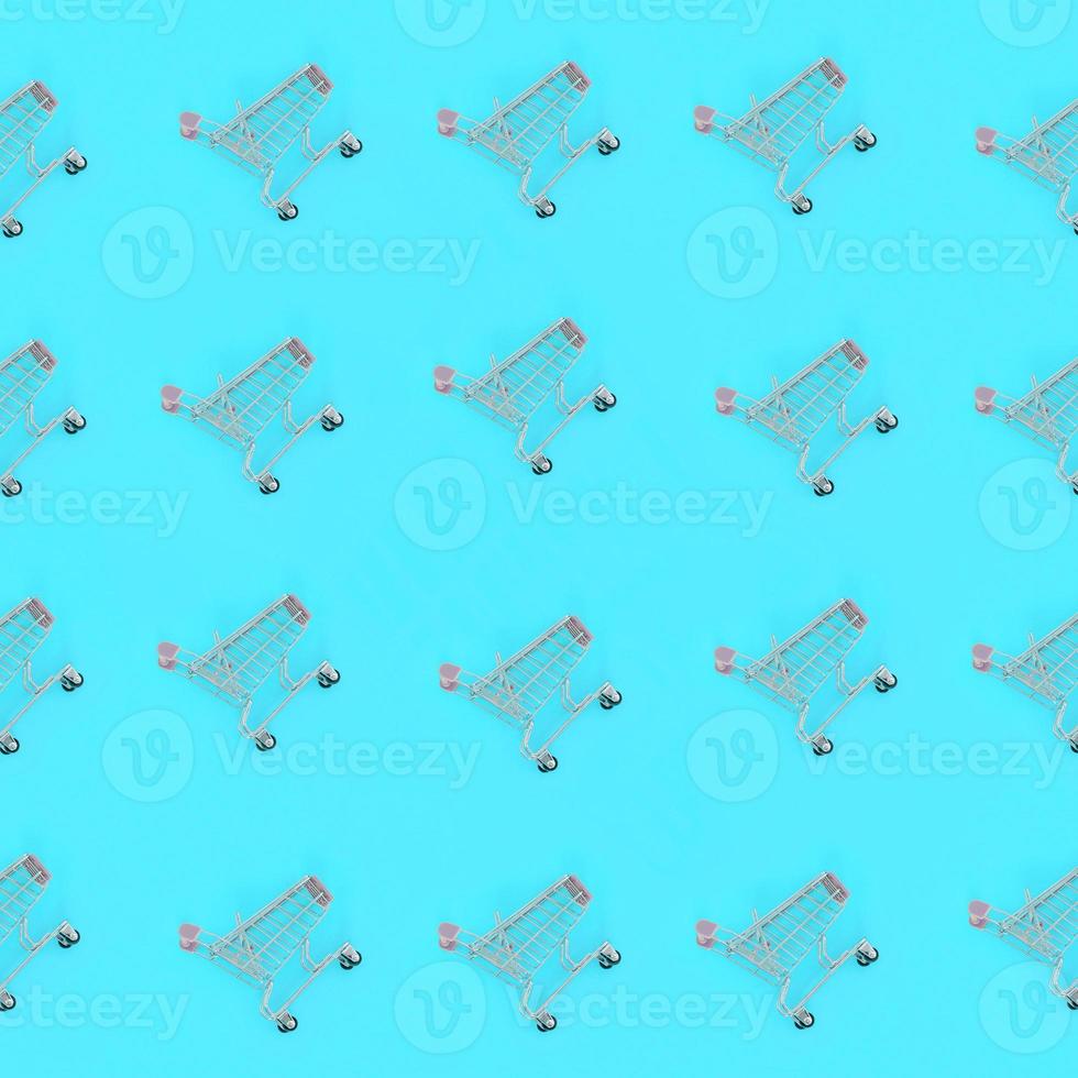 Shopping addiction, shopping lover or shopaholic concept. Many small empty shopping carts perform a pattern on a pastel colored paper background. Flat lay composition, top view photo