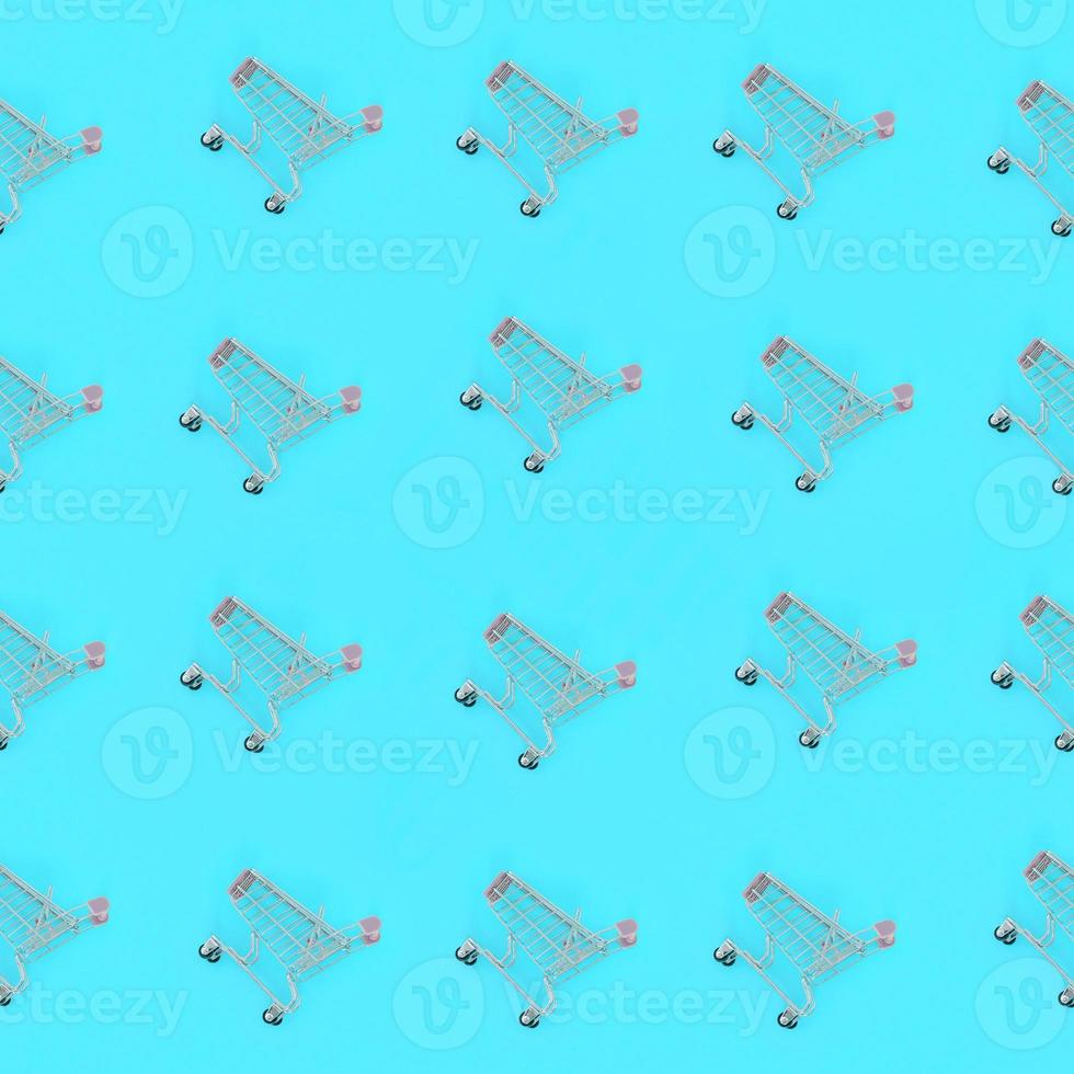 Shopping addiction, shopping lover or shopaholic concept. Many small empty shopping carts perform a pattern on a pastel colored paper background. Flat lay composition, top view photo