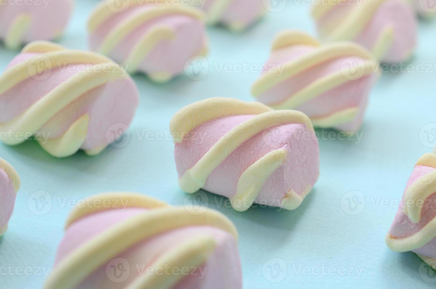 Colorful marshmallow laid out on blue paper background. pastel creative textured pattern. Perspective macro shot photo