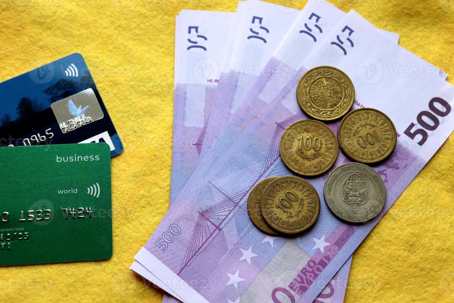 tarjetas de plástico de pago, billetes y monedas en un fondo amarillo foto