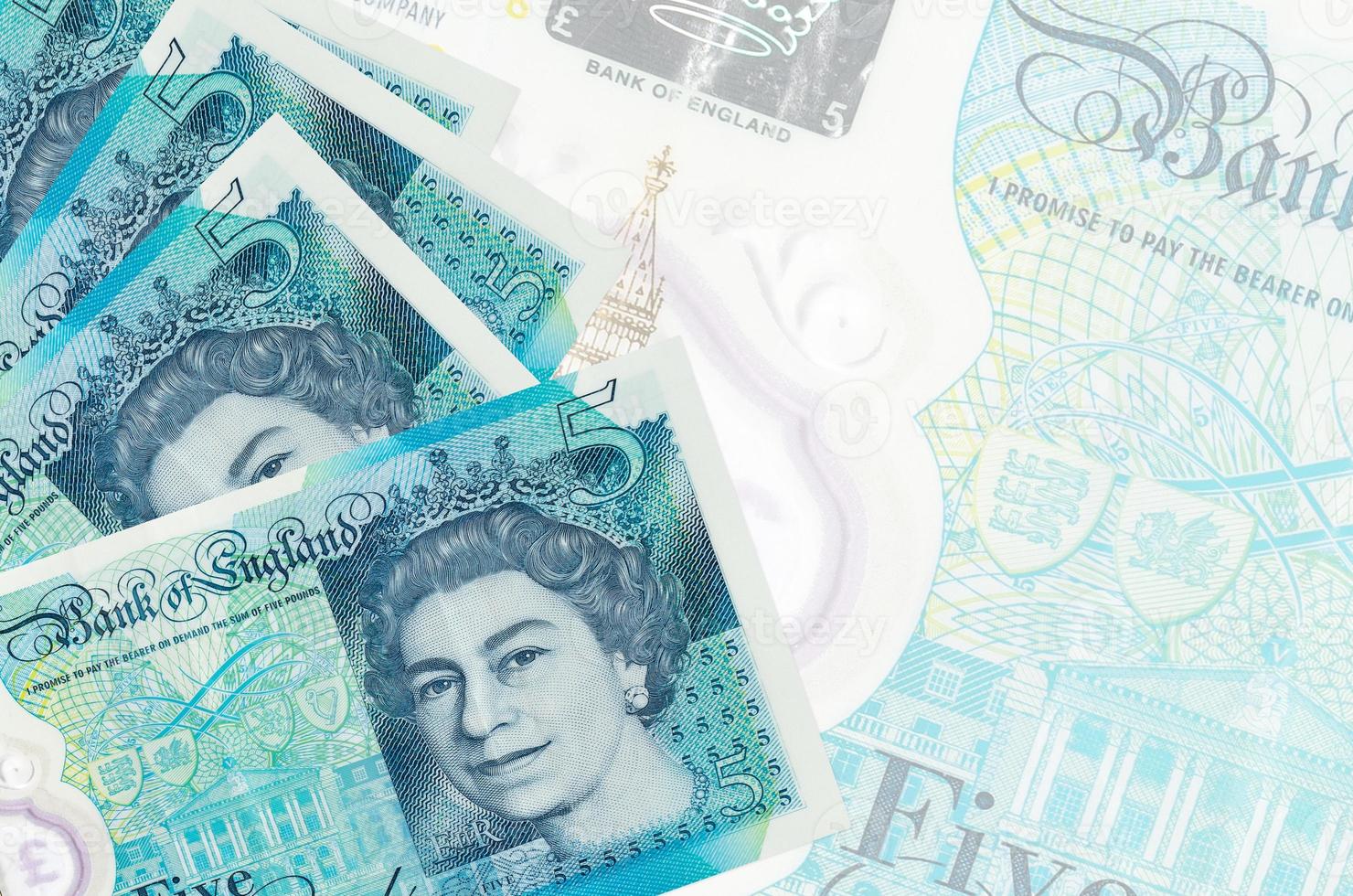 5 British pounds bills lies in stack on background of big semi-transparent banknote. Abstract business background photo