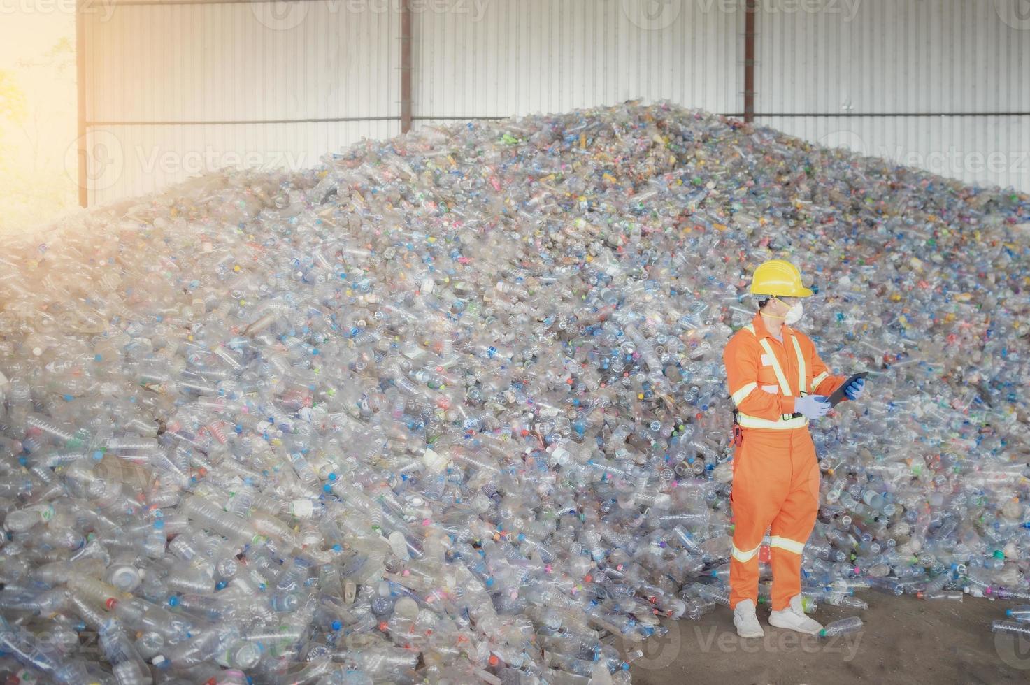 trabajadores en vertederos, ingenieros de basura, reciclaje, usando un traje de seguridad parados en el centro de reciclaje tienen una botella de plástico para reciclar en la fábrica foto