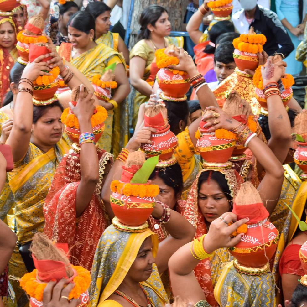 New Delhi, India April 03 2022 - Women with Kalash on head during Jagannath Temple Mangal Kalash Yatra, Indian Hindu devotees carry earthen pots containing sacred water with a coconut on top photo