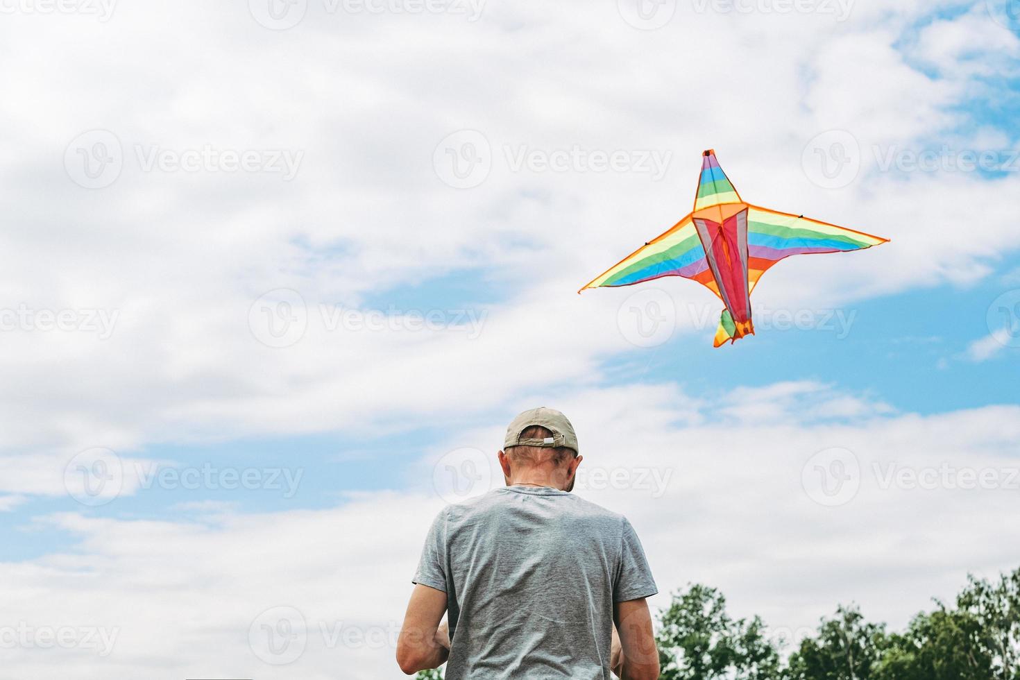 Silhouette of a young man flying a kite towards the sun. photo