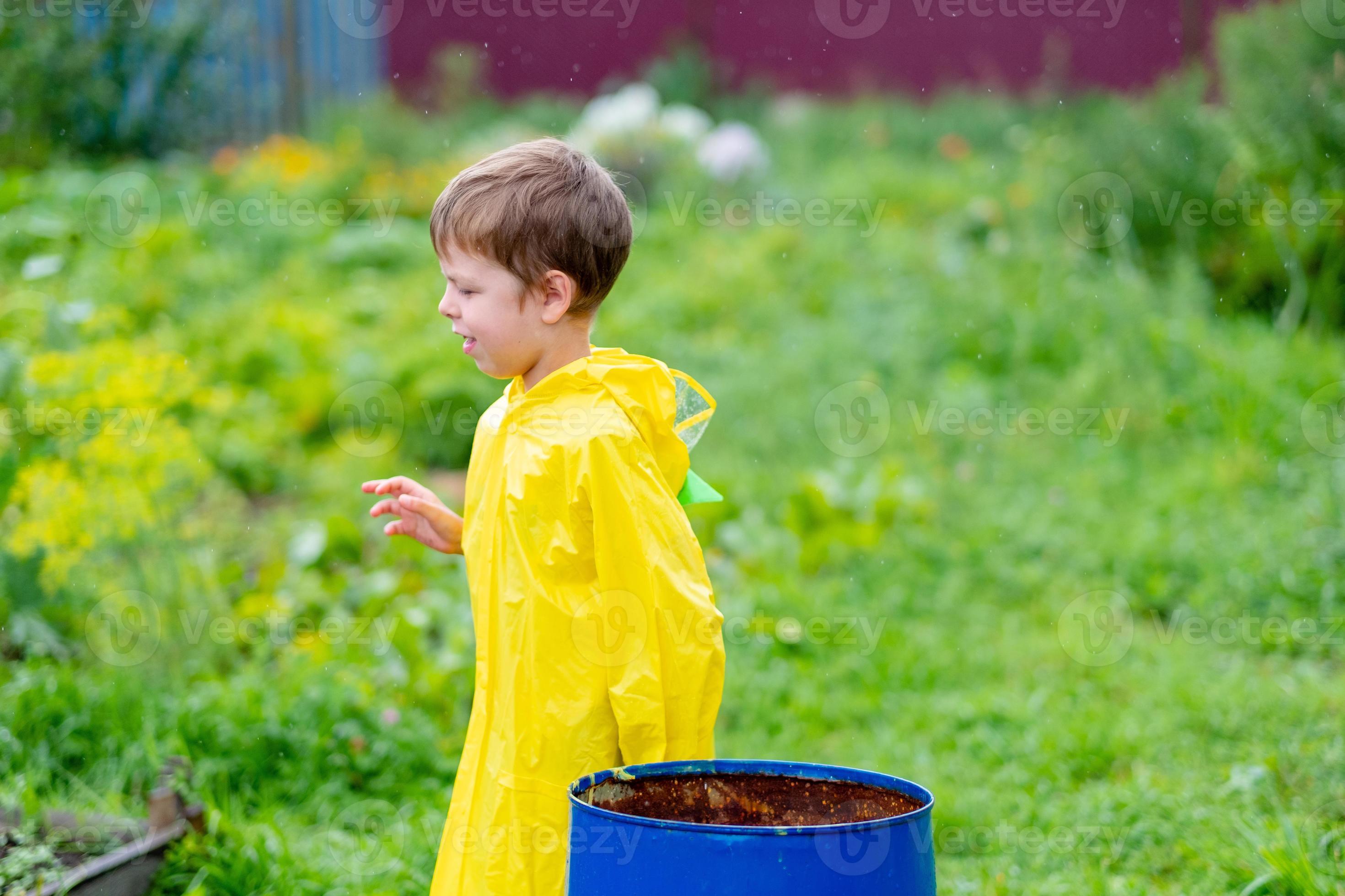 A boy in a yellow raincoat walks outside in the rain. Beautiful and