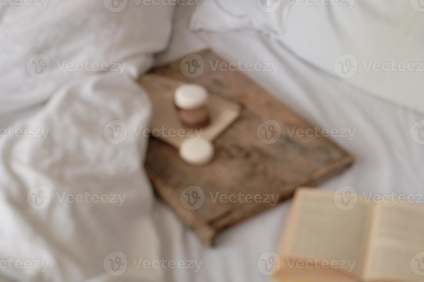 coffee with marshmallows and macaroons, book on a wooden tray, in bed. The photo is out of focus. Aesthetically beautiful frame. Desserts in bed. hot chocolate with marshmallows.