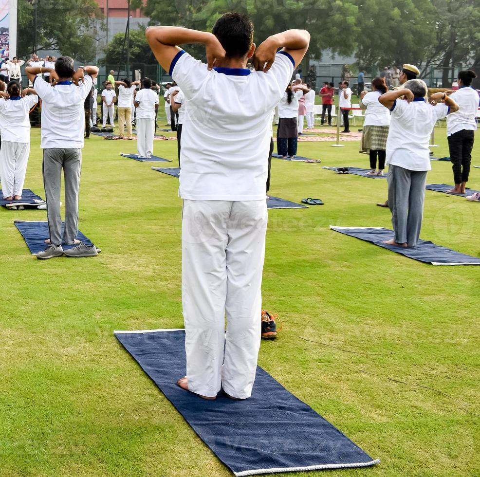 Group Yoga exercise session for people of different age groups at cricket stadium in Delhi on International Yoga Day, Big group of adults attending yoga session photo