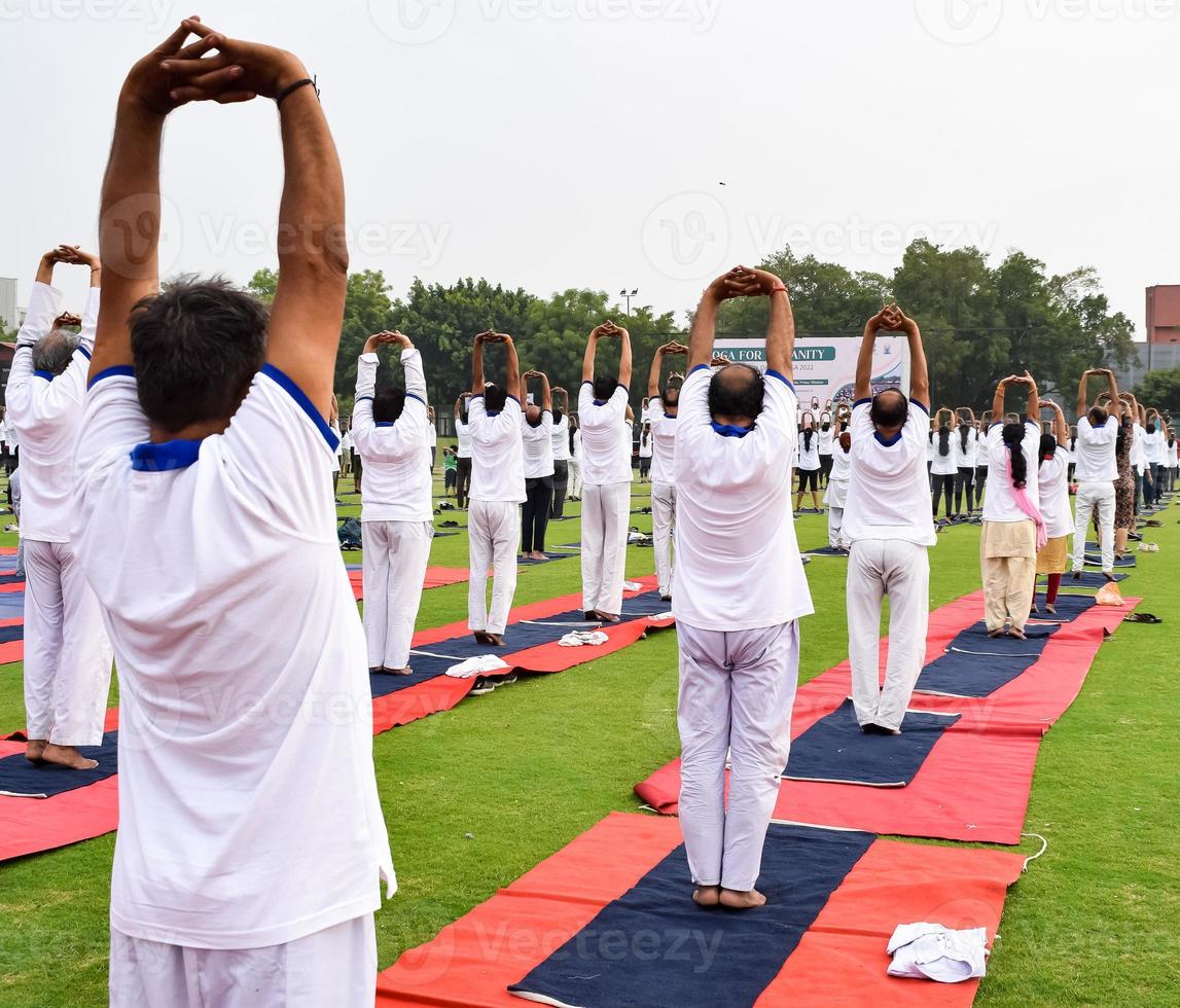 Group Yoga exercise session for people of different age groups at cricket stadium in Delhi on International Yoga Day, Big group of adults attending yoga session photo