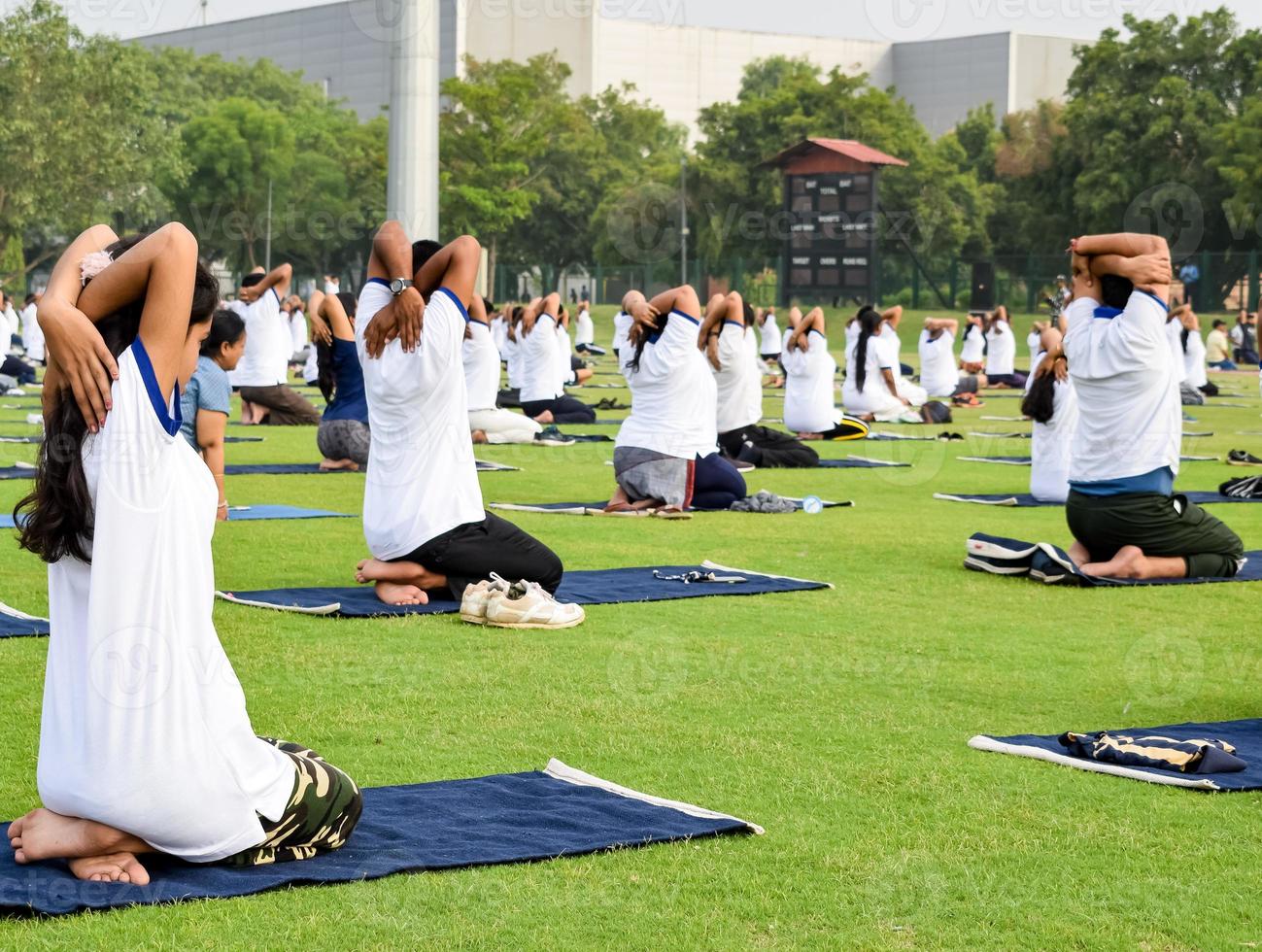 sesión de ejercicios de yoga en grupo para personas de diferentes grupos de edad en el estadio de cricket en delhi el día internacional del yoga, gran grupo de adultos que asisten a la sesión de yoga foto