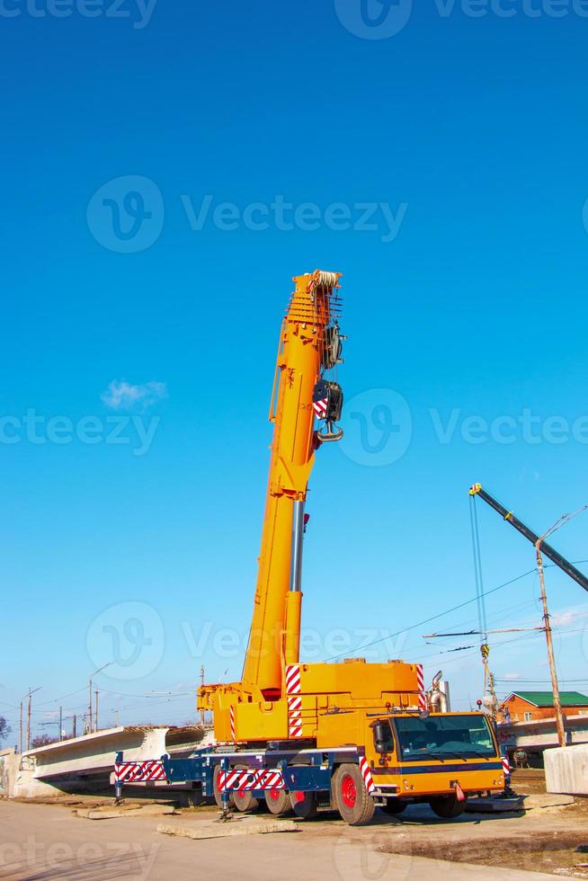Heavy truck crane with an arrow. Raised boom of a truck crane against the sky photo