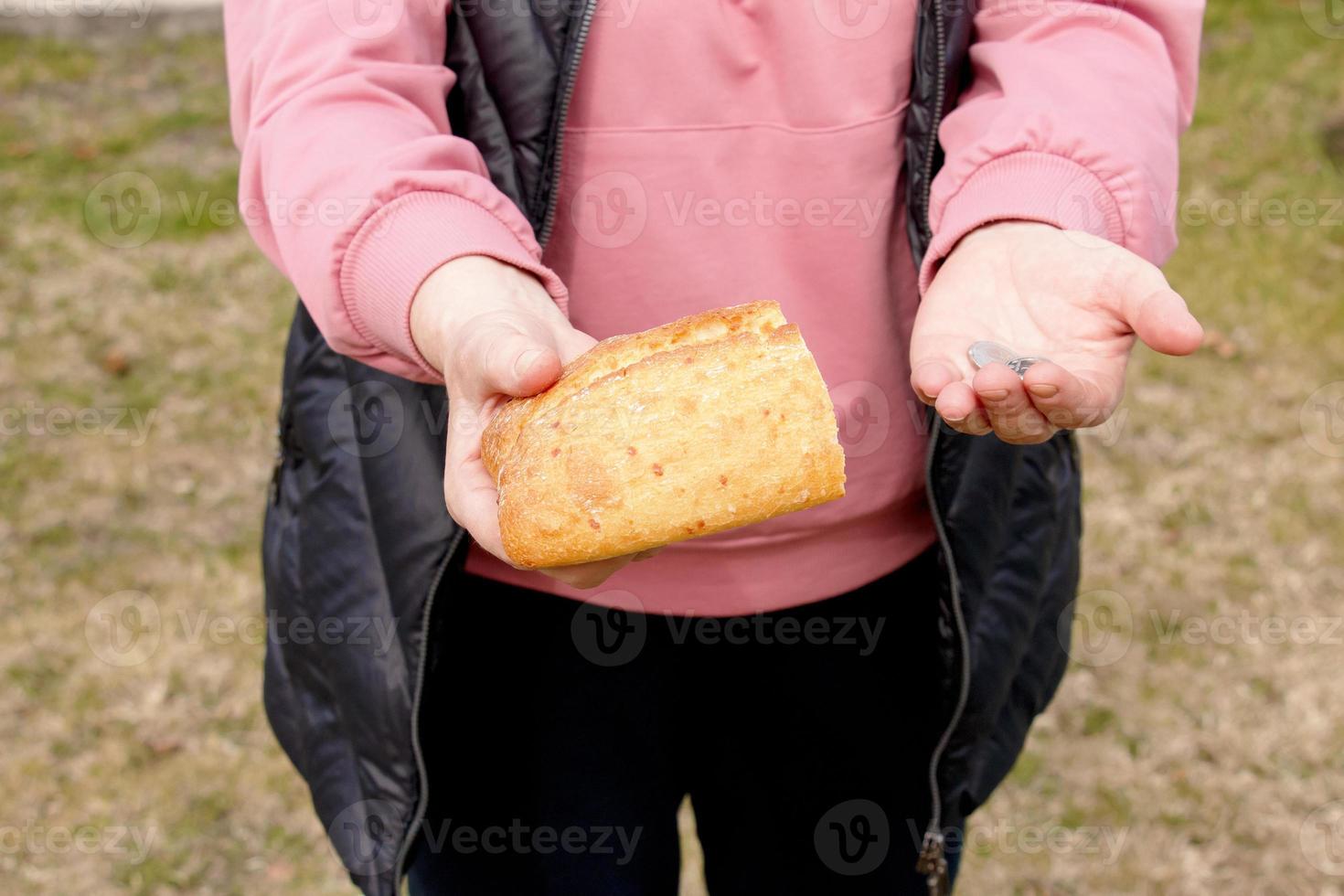 Last money for bread. Bread in the hand of a middle-aged woman. The concept of the world food crisis associated with the war in Ukraine photo