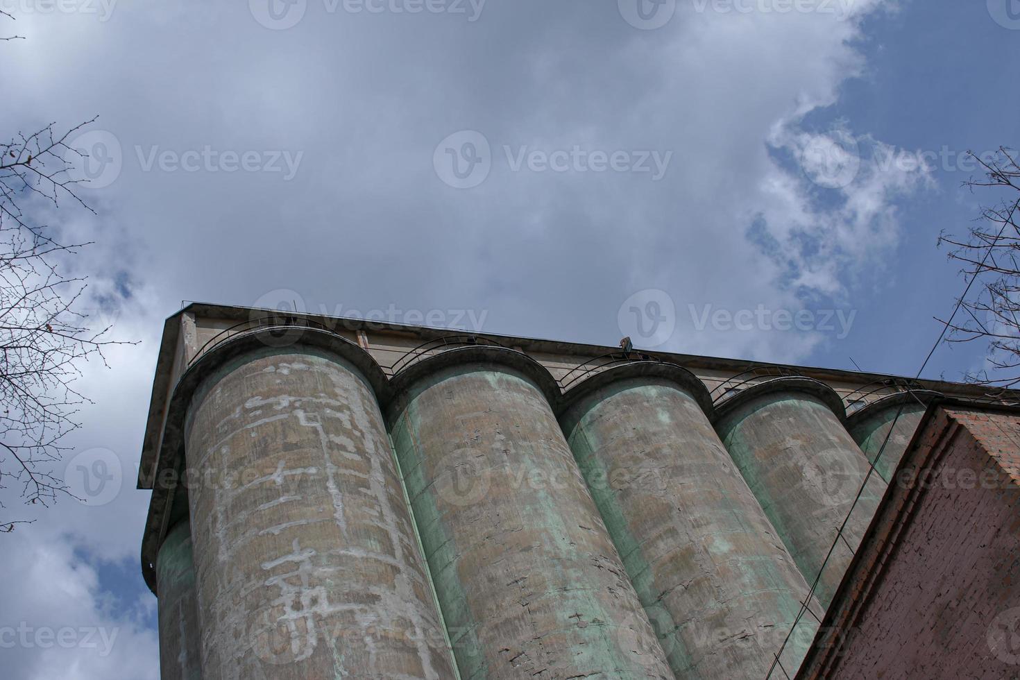 Grain elevator against a stormy sky. Large factory structure against a blue sky, low angle view. photo