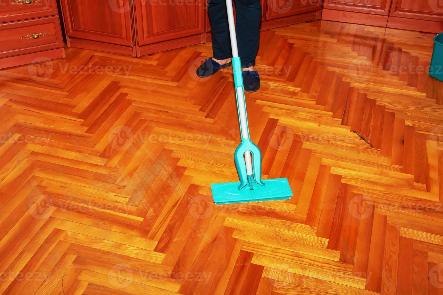 Mop your wood floor. A woman washes the parquet with a mop with a