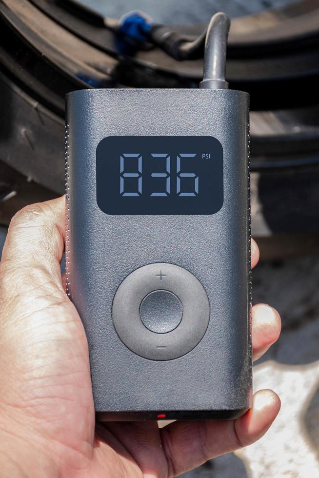 Hand holding a portable inflator is inflating a motorcycle tire. photo