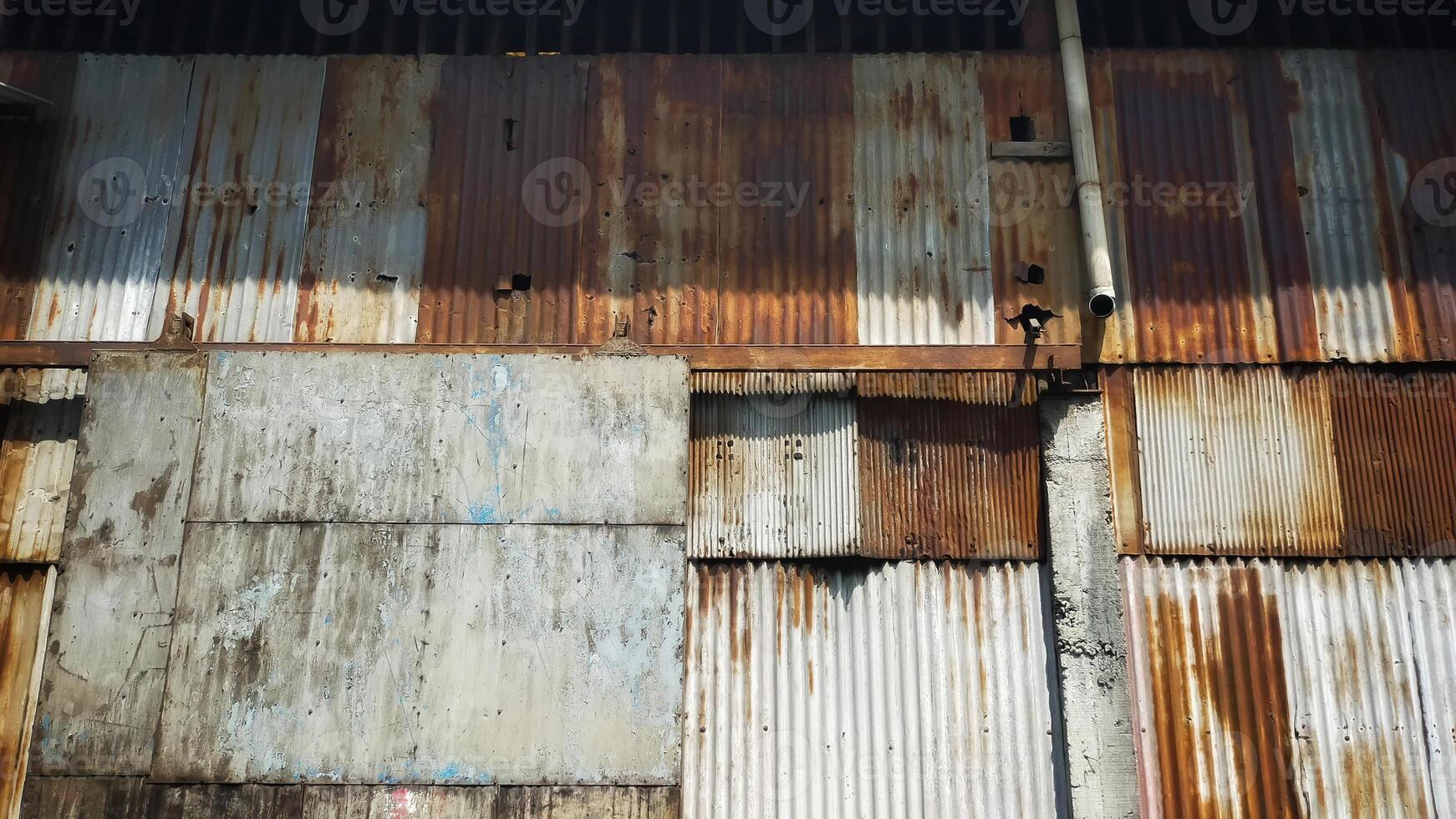 Old building covered with rusty corrugated tin walls and rolling door. photo