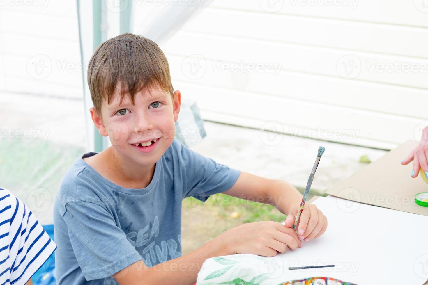 a boy draws at a table in the street photo