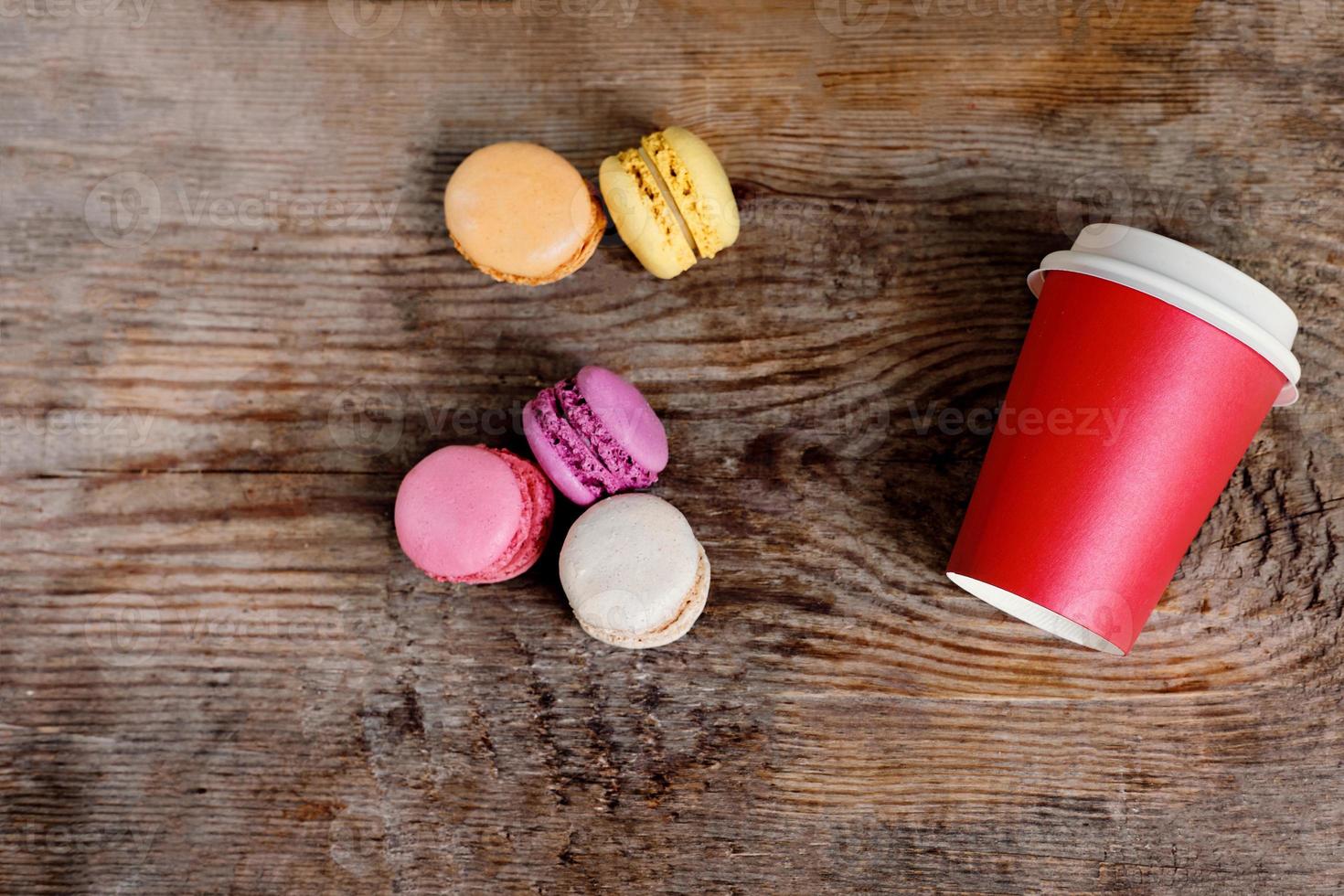 red paper cup with coffee and macaroons on a wooden background. Coffee to go with cakes with copy space photo
