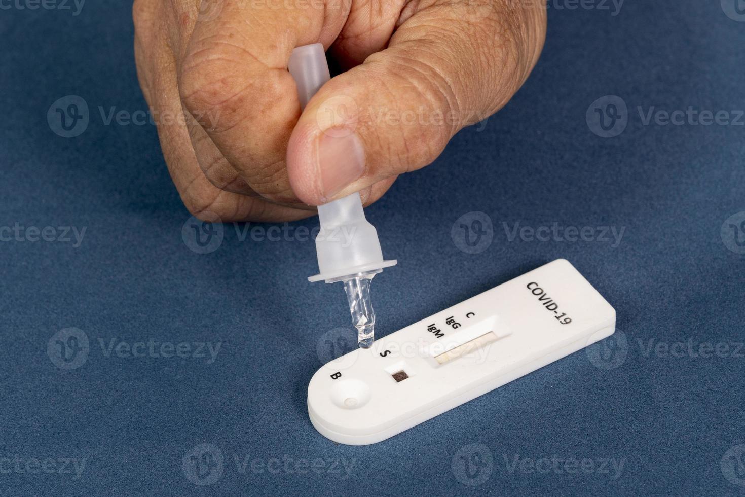 Covid-19 rapid test with person dripping the reagent photo