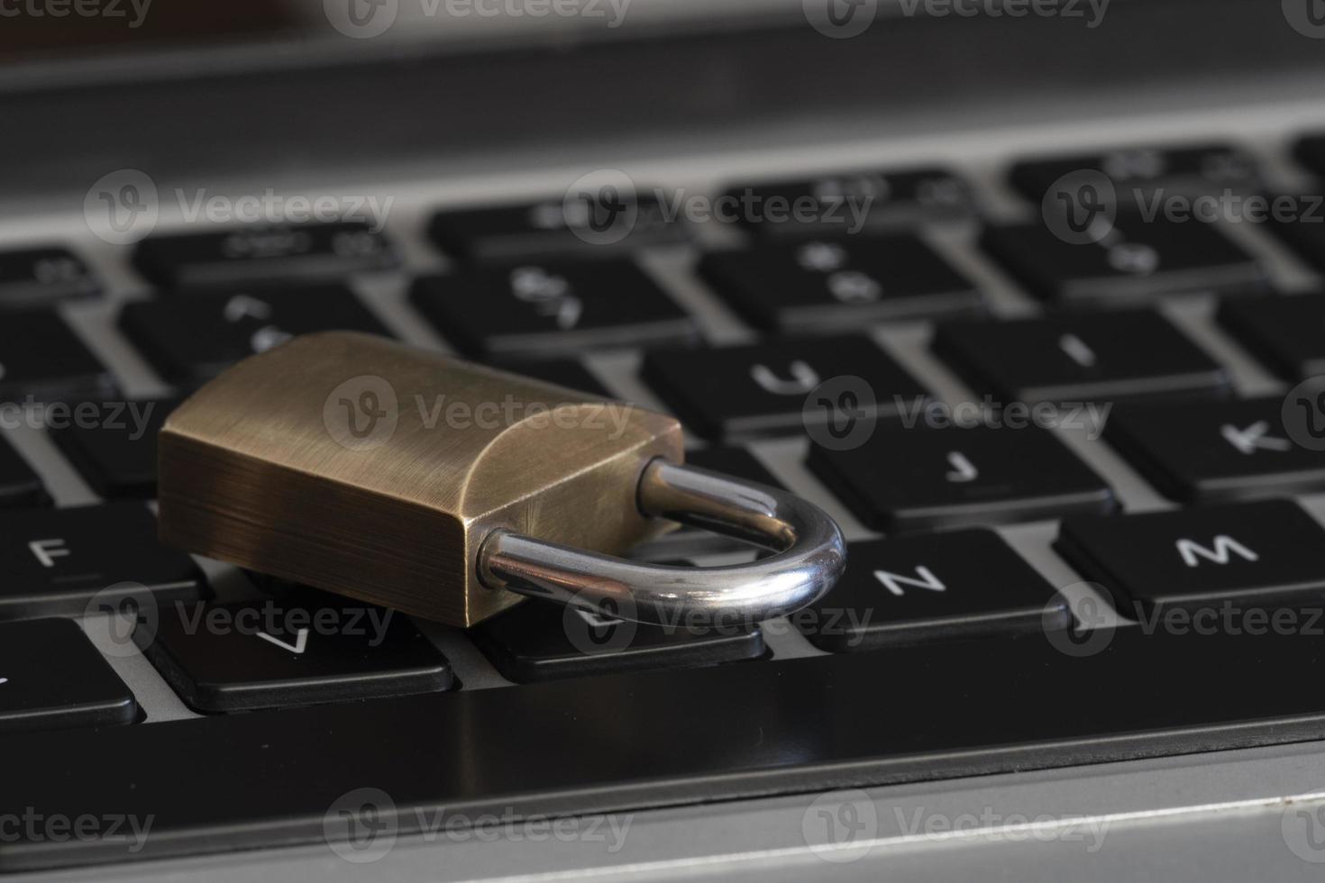Internet y seguridad informática representada por un candado cerrado sobre un teclado negro foto
