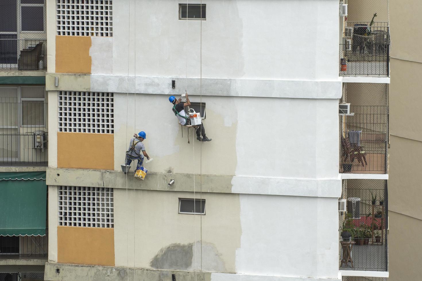 rio, brasil - 04 de noviembre de 2022, pintor trabaja en la recuperación de fachadas de edificios residenciales por cuerda como escalador foto