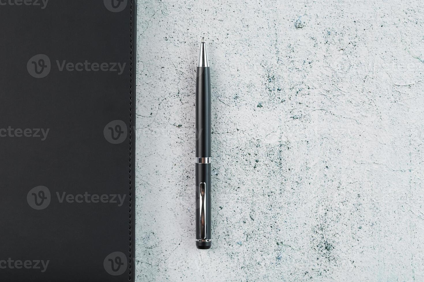 Black Notepad with a black pen on a gray background photo