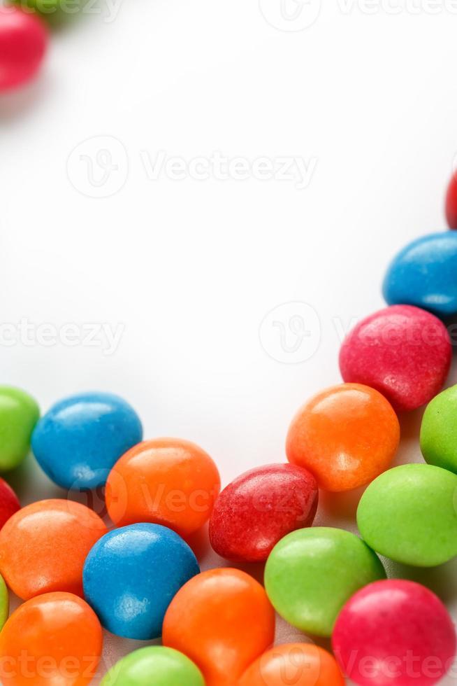 A rainbow of color from multicolored candies close-up, multi-colored glaze dragee on a white background photo